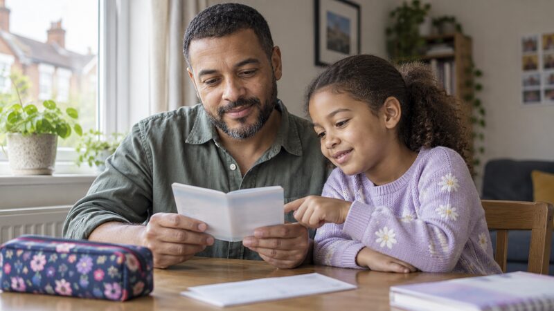 A parent and child looking at a junior savings passbook together