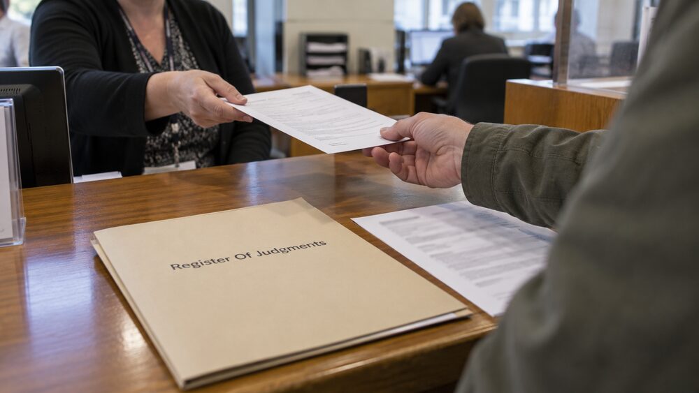 Hands hold a debit card beside an open laptop and a blurred receipt on a table.