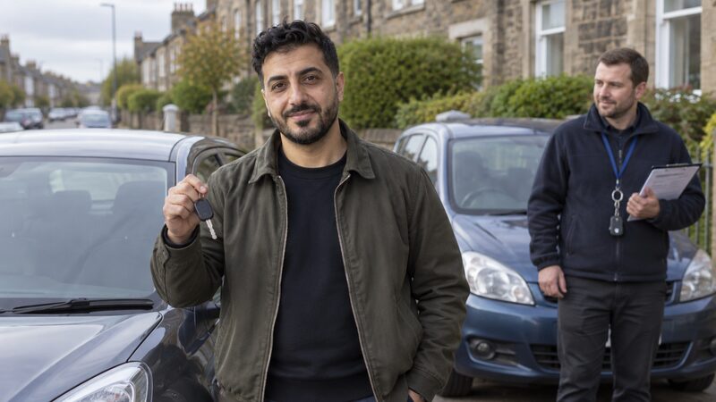 A car buyer holding loan paperwork beside a car on a dealership forecourt