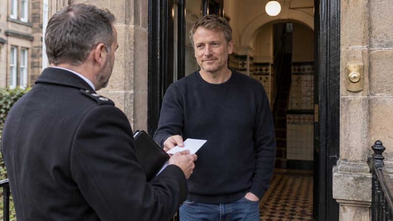 A man receives an envelope from an officer at his tenement doorstep.